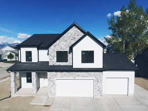 Modern farmhouse style home featuring a garage, concrete driveway, roof with shingles, and stone siding