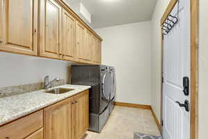 Laundry room with separate washer and dryer, light tile patterned flooring, a sink, baseboards, and cabinet space