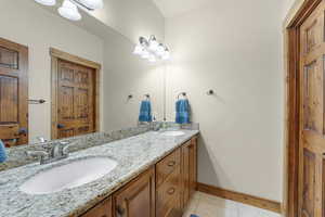 Full bathroom with double vanity, a sink, tile patterned flooring, and baseboards