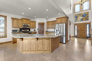 Kitchen featuring baseboards, a sink, a kitchen breakfast bar, recessed lighting, and stainless steel appliances