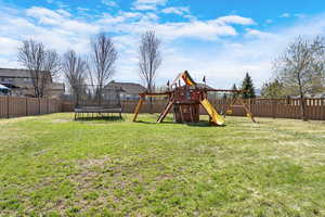 View of yard featuring a trampoline, a fenced backyard, and a playground
