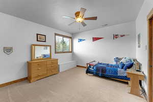 Bedroom with light colored carpet, baseboards, and ceiling fan
