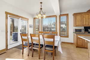 Dining area featuring visible vents, a chandelier, light tile patterned flooring, baseboards, and a toaster