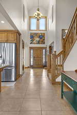 Foyer featuring a chandelier, plenty of natural light, stairway, and high vaulted ceiling