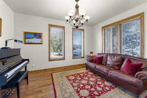 Living area with baseboards, a notable chandelier, and hardwood / wood-style flooring