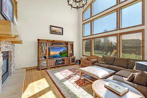 Living room featuring a notable chandelier, hardwood / wood-style floors, a high ceiling, and baseboards