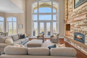 Living area with a high ceiling, ornamental molding, wood finished floors, and a stone fireplace