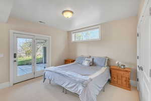 Bedroom featuring baseboards, visible vents, light colored carpet, and access to exterior