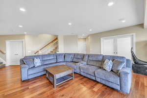 Living room with stairway, recessed lighting, and light wood-type flooring