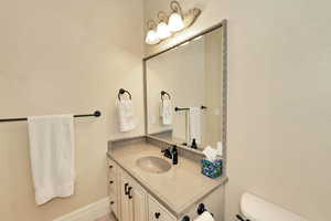 Bathroom featuring baseboards, toilet, and vanity