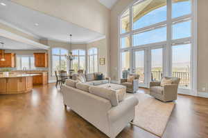 Living area with wood finished floors, baseboards, an inviting chandelier, and ornamental molding