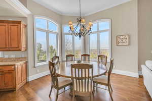 Dining room with baseboards, light wood-style floors, a notable chandelier, and ornamental molding