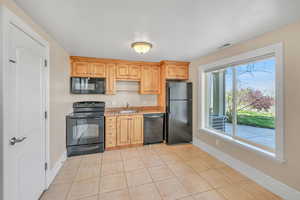 Kitchen featuring a sink, baseboards, visible vents, black appliances, and light tile patterned floors