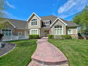 View of front of home with roof with shingles, fence, stone siding, and a front yard
