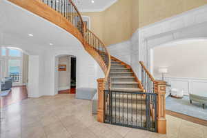 Stairs featuring tile patterned floors, arched walkways, recessed lighting, crown molding, and a decorative wall