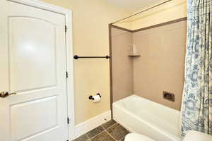 Bathroom with shower / tub combo with curtain, toilet, and baseboards