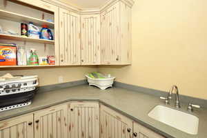 Kitchen with open shelves, a sink, and cream cabinets