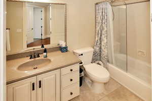 Bathroom featuring shower / bath combo, toilet, vanity, and tile patterned flooring