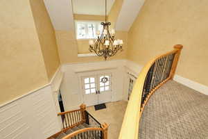 Entrance foyer featuring stairs, french doors, high vaulted ceiling, and a chandelier