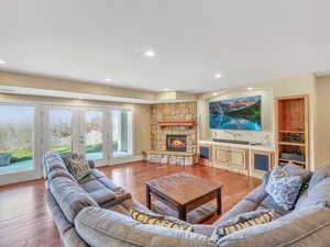 Living room with plenty of natural light, a stone fireplace, wood finished floors, and recessed lighting