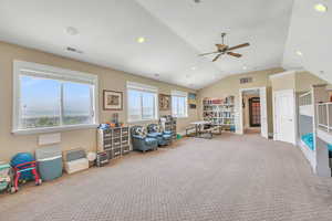 Recreation room featuring lofted ceiling, carpet, visible vents, and a ceiling fan