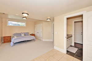 Carpeted bedroom featuring baseboards, tile patterned floors, and a closet