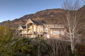 View of front of property featuring an attached garage, a balcony, stucco siding, and a mountain view