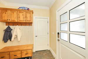 Mudroom with stone finish flooring, baseboards, and ornamental molding