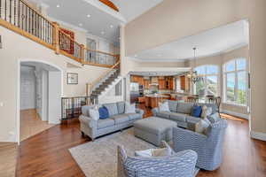 Living area with a high ceiling, an inviting chandelier, stairway, and crown molding