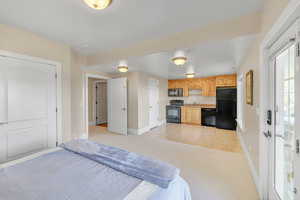 Bedroom with light colored carpet, baseboards, a sink, and freestanding refrigerator