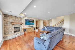 Living area featuring baseboards, visible vents, stairway, hardwood / wood-style floors, and a fireplace