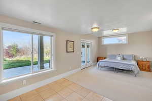 Bedroom featuring light carpet, light tile patterned flooring, visible vents, and baseboards