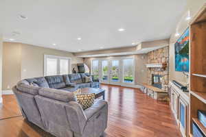 Living area with french doors, a fireplace, wood-type flooring, baseboards, and recessed lighting