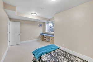 Carpeted bedroom featuring built in desk and baseboards