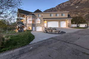 View of front of home with concrete driveway, a mountain view, fence, a garage, and stucco siding