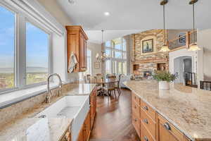 Kitchen with a towering ceiling, light stone counters, a sink, hanging light fixtures, and a notable chandelier