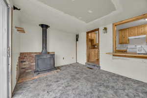 Unfurnished living room with carpet flooring and a wood stove
