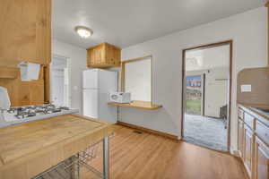Kitchen featuring light countertops, visible vents, a sink, white appliances, and light wood-style floors