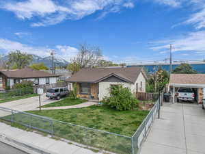 View of front of home with a fenced front yard, roof with shingles, a front lawn, and concrete driveway