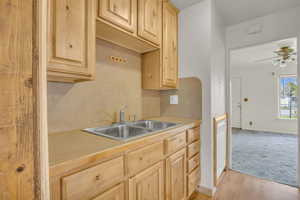 Kitchen featuring light countertops, light wood finished floors, light brown cabinetry, and a sink