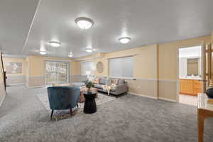 Living area featuring a textured ceiling, baseboards, and light carpet