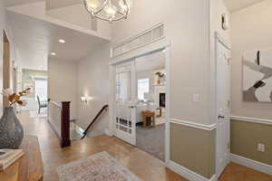 Tiled entryway featuring recessed lighting, a glass covered fireplace, baseboards, and a notable chandelier