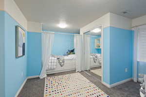 Bedroom with baseboards, carpet flooring, and textured ceiling