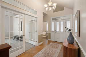 Entrance foyer with french doors, baseboards, an inviting chandelier, and vaulted ceiling