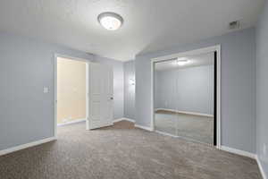 Bedroom with carpet floors, baseboards, a textured ceiling, and a closet
