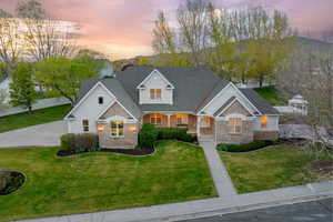 View of front of house with a lawn, a porch, and stone siding