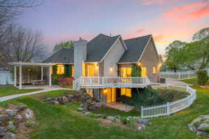 Rear view of property featuring a lawn, a chimney, a patio area, and a deck