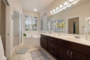 Full bath featuring a bath, tile patterned floors, a sink, and double vanity