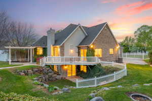 Rear view of house featuring a chimney, fence, a wooden deck, a yard, and stucco siding