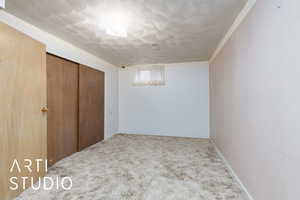 Below grade area with a textured ceiling, baseboards, crown molding, and carpet floors